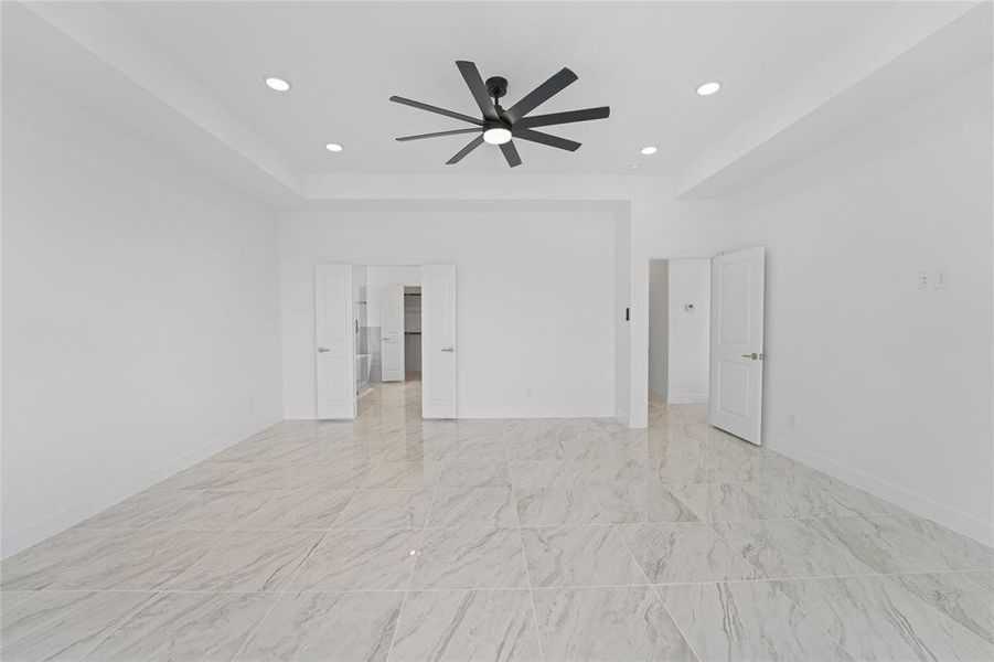 Unfurnished room with a tray ceiling, ceiling fan, and light tile floors