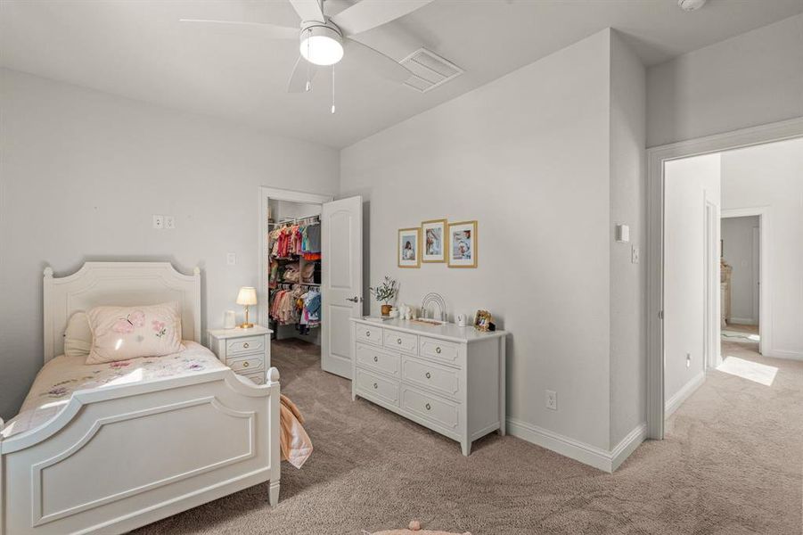 Bedroom featuring a closet, ceiling fan, light carpet, and a walk in closet