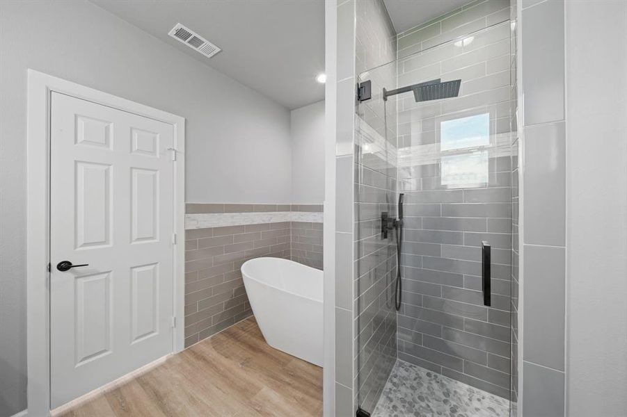 Bathroom with shower with separate bathtub, tile walls, and hardwood / wood-style floors