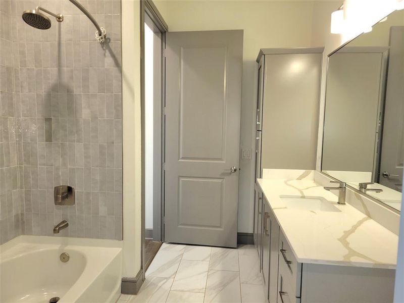 Bathroom with tile flooring, large vanity, and tiled shower / bath