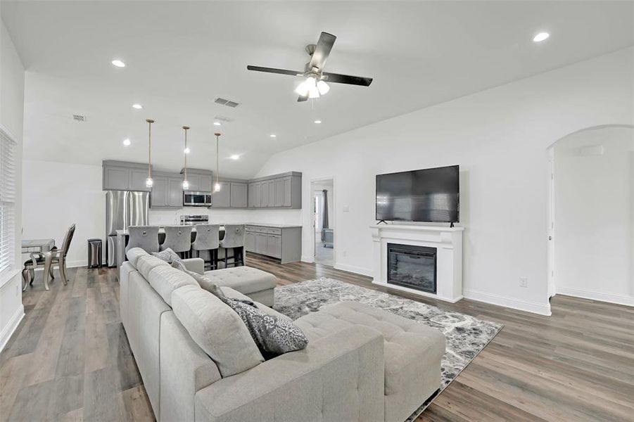 Living room featuring light hardwood / wood-style floors, ceiling fan, and lofted ceiling