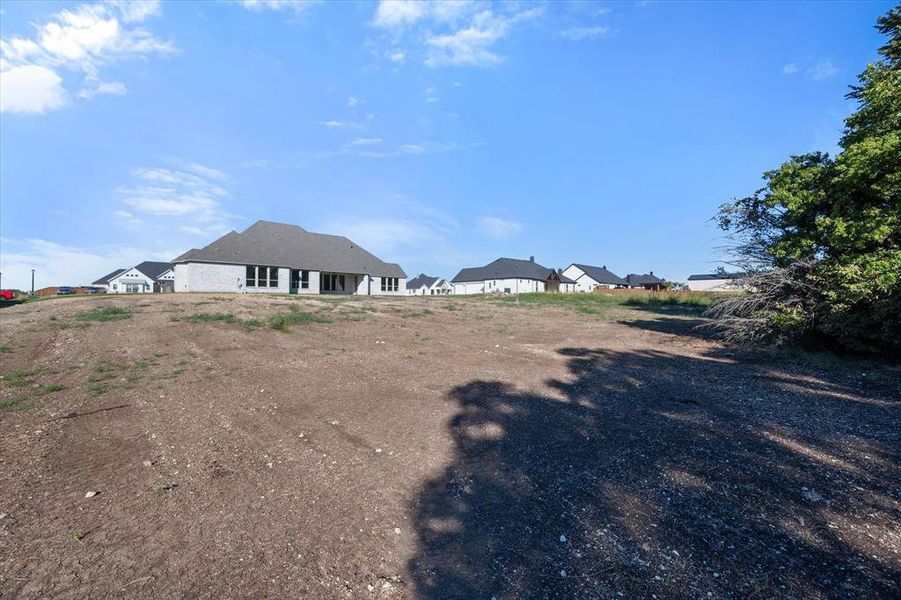 View of the house from the tree line in backyard. 1.649 acre lot backing to a greenbelt. Lot extends past the back tree line.