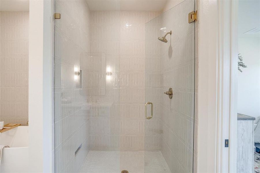 The walk in shower offers ample space and is finished with Delta fixtures and custom tile work.