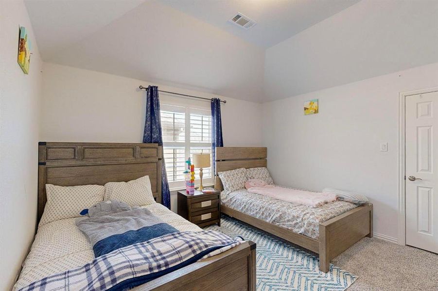 Bedroom with vaulted ceiling and light colored carpet