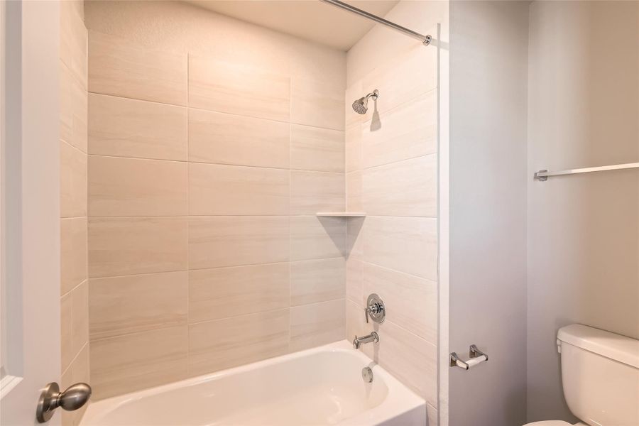 The secondary bathroom water closet hosts the shower/tub combo with the same gorgeous tile backsplash as the primary suite along with the commode.