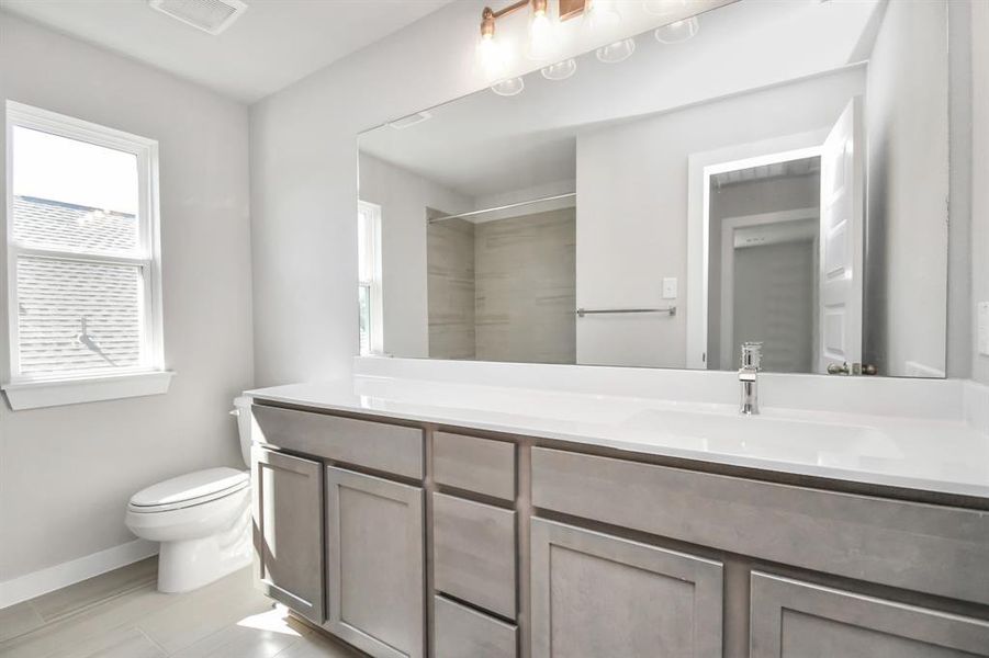 Experience sophistication in the secondary bathroom, where tile flooring complements a bath/shower combo with tile surround. Dark wood cabinets complete with a beautiful light countertop, enhances the space for a truly inviting ambiance.