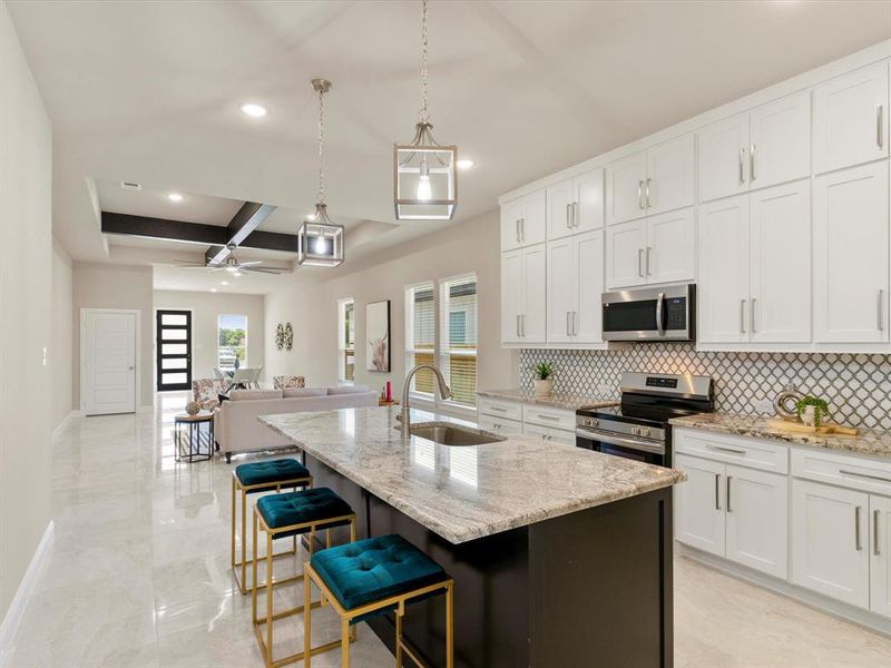 Kitchen with pendant lighting, sink, an island with sink, stainless steel appliances, and ceiling fan