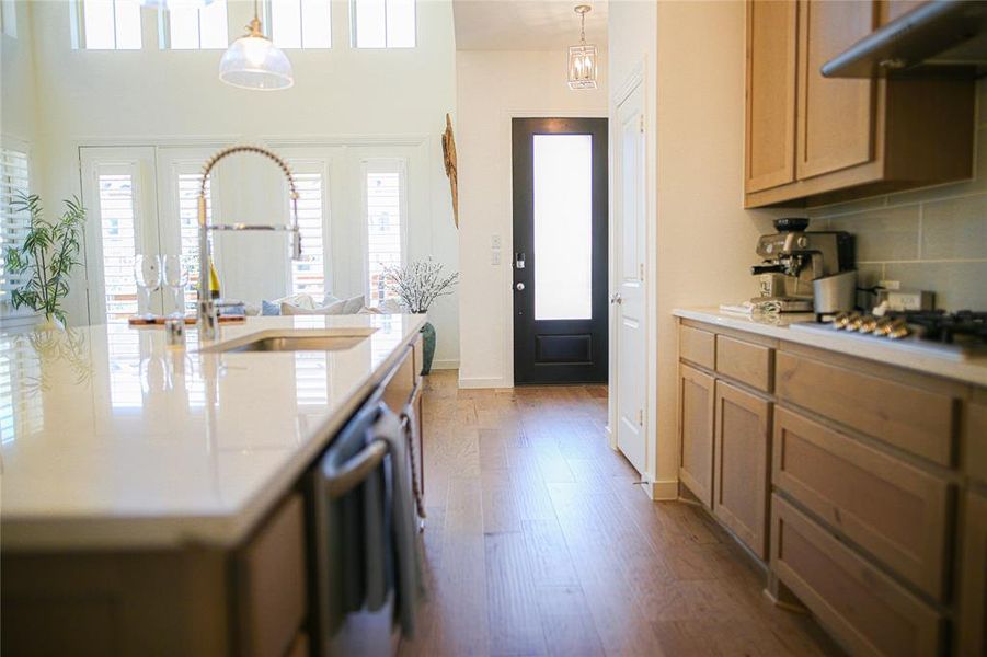 Kitchen with tasteful backsplash, light wood-type flooring, extractor fan, and decorative light fixtures