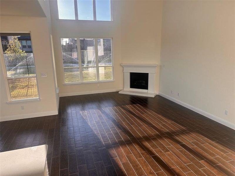 Unfurnished living room with a towering ceiling and dark wood-type flooring