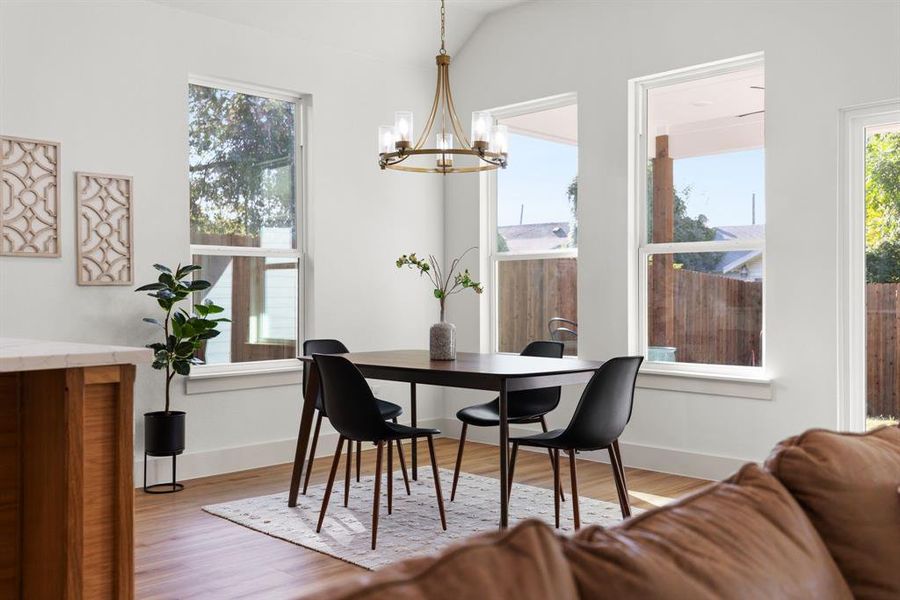 Dining room featuring an inviting chandelier, light hardwood / wood-style flooring, and lofted ceiling