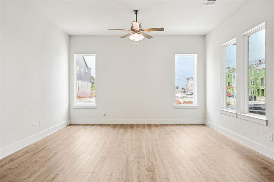 Empty room featuring ceiling fan, plenty of natural light, and light hardwood / wood-style flooring