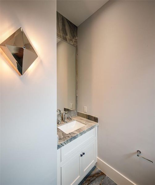 Dedicated powder room off the game room with elegant wall sconces and gorgeous matching counter and floor tile