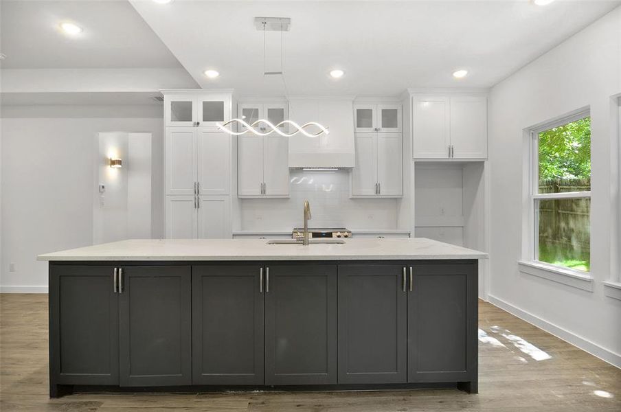 Kitchen with sink, light hardwood / wood-style flooring, decorative backsplash, and pendant lighting