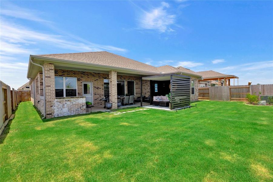 Expansive Backyard - Expansive space for endless possibilities, showing extra greenspace and the custom patio with an outdoor kitchen and pergola.