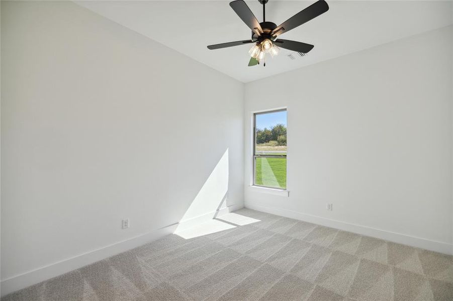 Carpeted spare room featuring ceiling fan