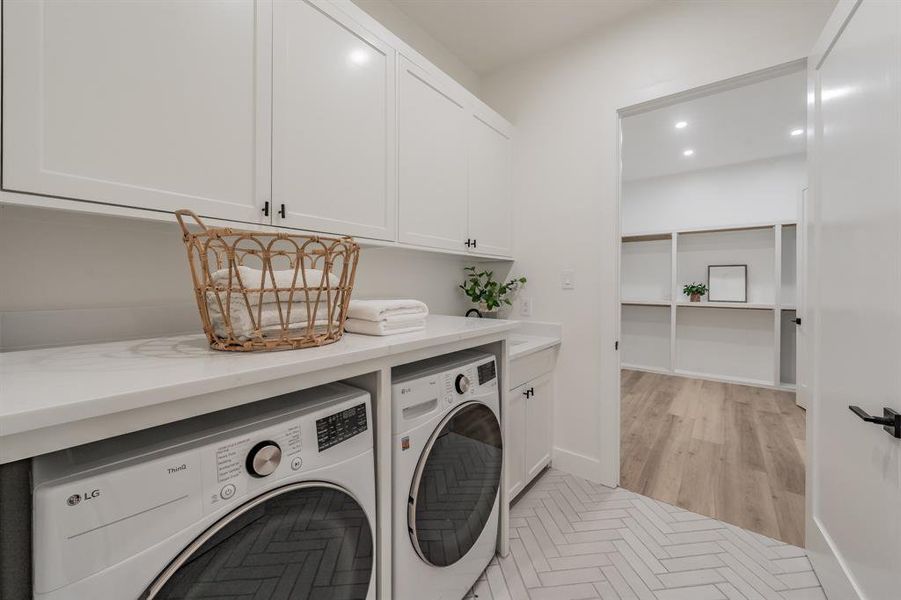 Laundry area featuring separate washer and dryer, blonde plank, wood-like luxury vinyl floors and cabinets