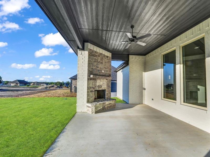 View of patio with ceiling fan and an outdoor stone fireplace