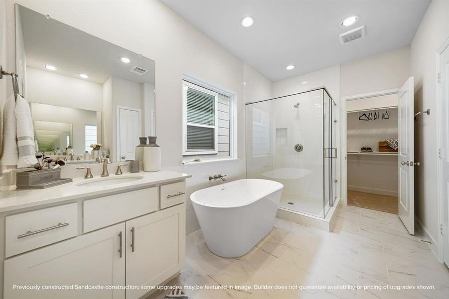 Indulge in a spa-like experience with a freestanding tub, step-in shower, dual sinks, a private water closet, and ample storage.