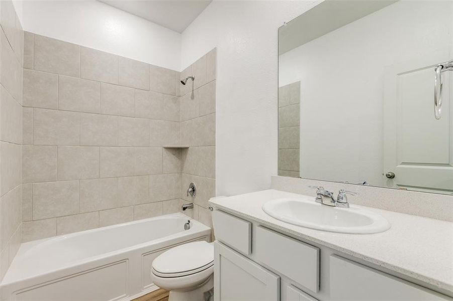 Full bathroom featuring vanity, tiled shower / bath, and toilet