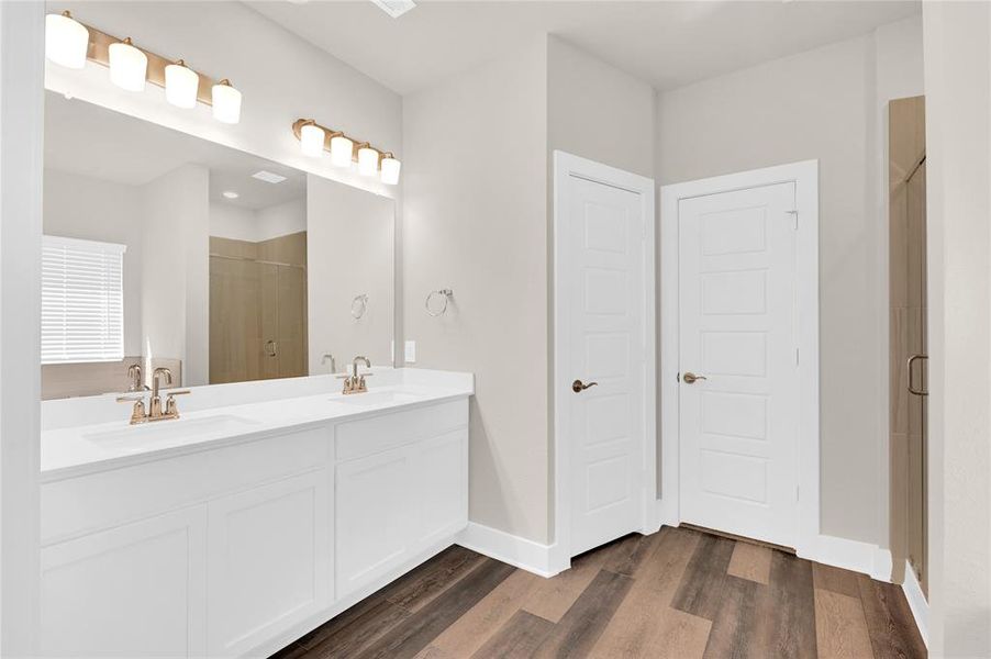 Your primary ensuite bathroom boasts beautiful bronze fixtures paired with crisp white counters and vanities, gorgeous luxury vinyl plank flooring, private water closet, soaking tub, and separate glass shower.