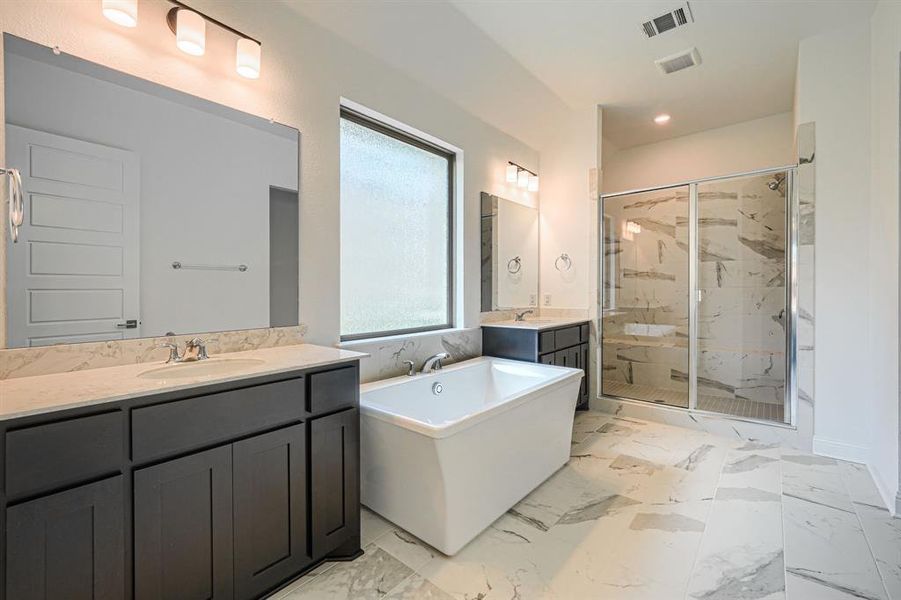 Bathroom with tile flooring, vanity with extensive cabinet space, and independent shower and bath