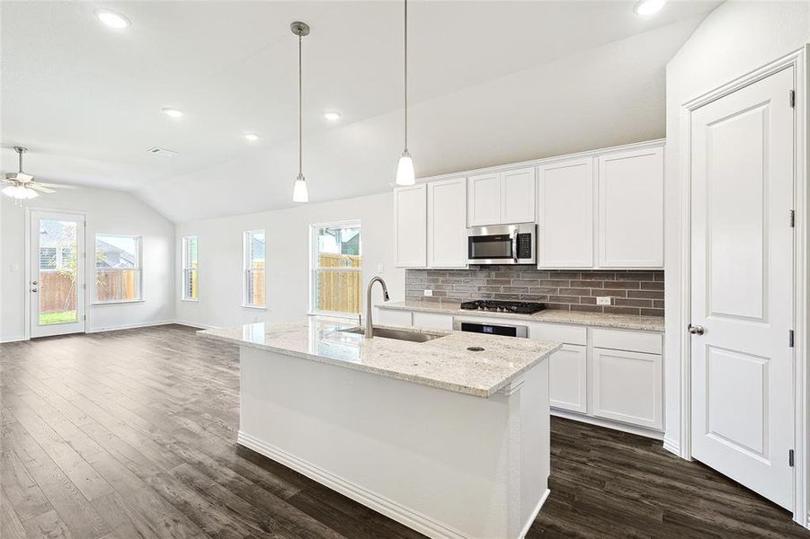 Kitchen with white cabinets, vaulted ceiling, sink, and ceiling fan