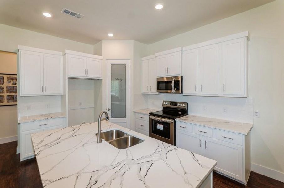 Kitchen featuring dark hardwood / wood-style floors, a kitchen island with sink, stainless steel appliances, sink, and white cabinets