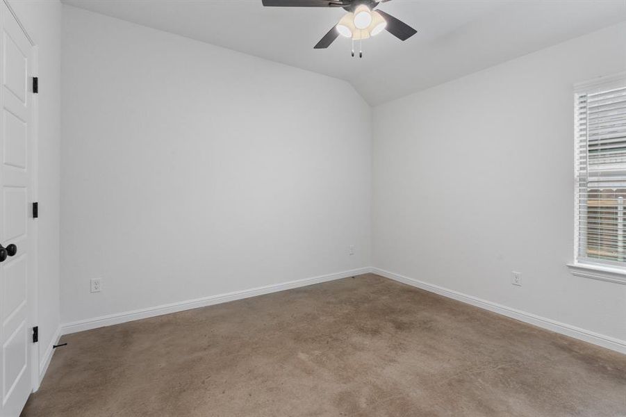 Carpeted spare room with ceiling fan, plenty of natural light, and vaulted ceiling