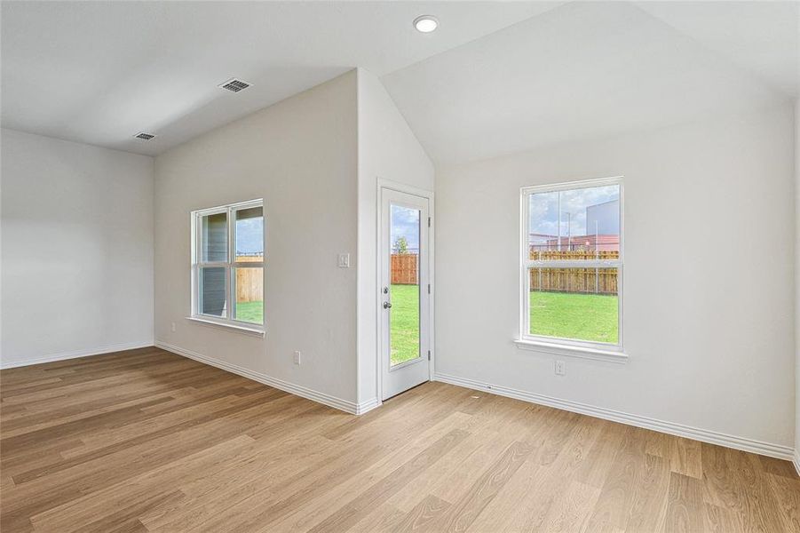 Unfurnished room with plenty of natural light, vaulted ceiling, and light hardwood / wood-style floors