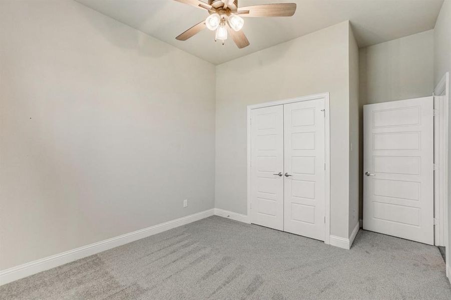 Unfurnished bedroom with ceiling fan, a closet, and light carpet