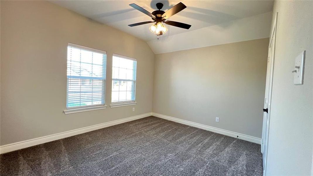 Unfurnished room with vaulted ceiling, ceiling fan, and dark carpet