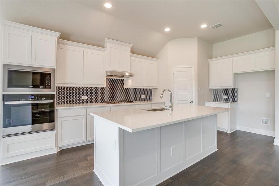 Kitchen featuring a center island with sink, appliances with stainless steel finishes, dark hardwood / wood-style floors, and sink