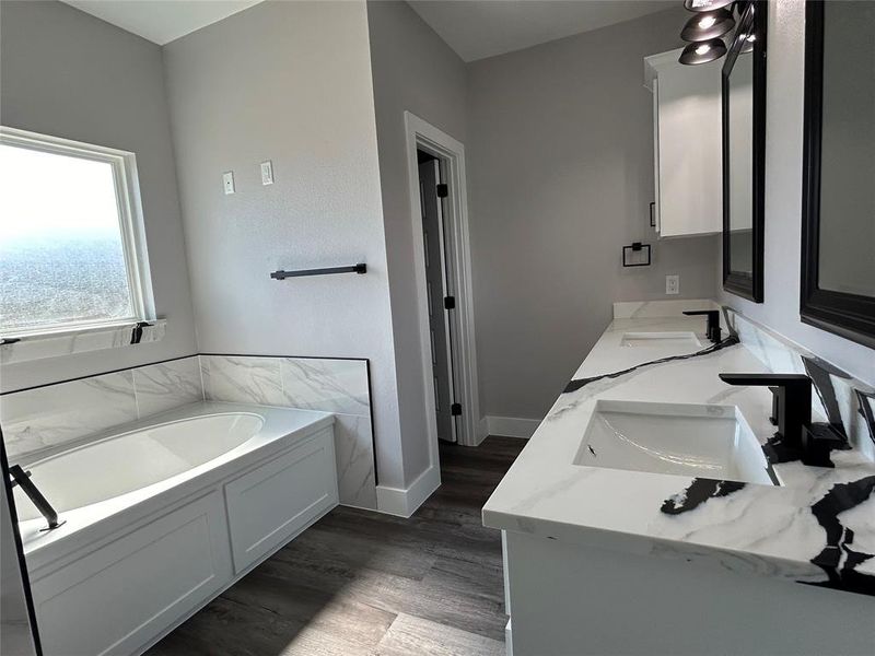 Bathroom with hardwood / wood-style floors, a tub, and vanity