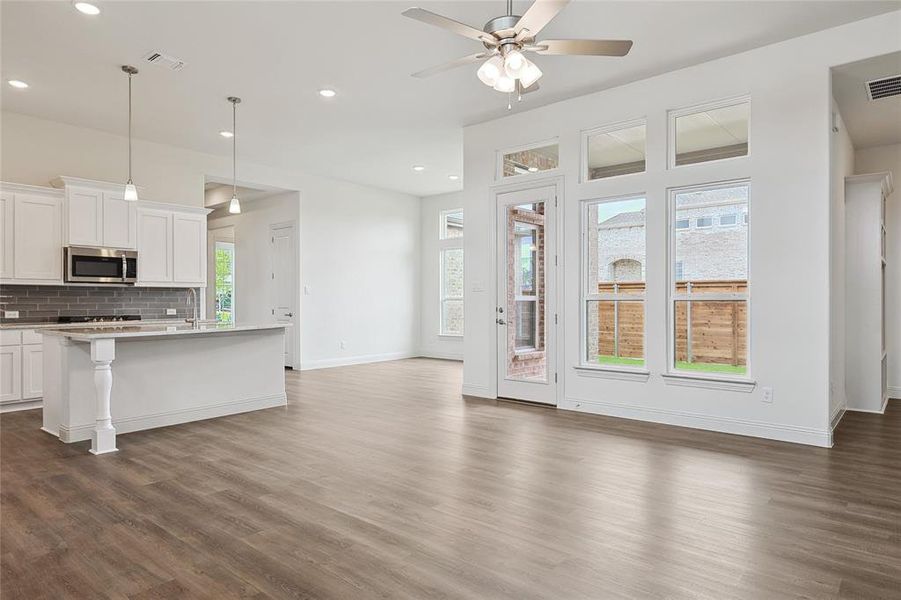 Kitchen with ceiling fan, hanging light fixtures, white cabinetry, dark hardwood / wood-style flooring, and decorative backsplash