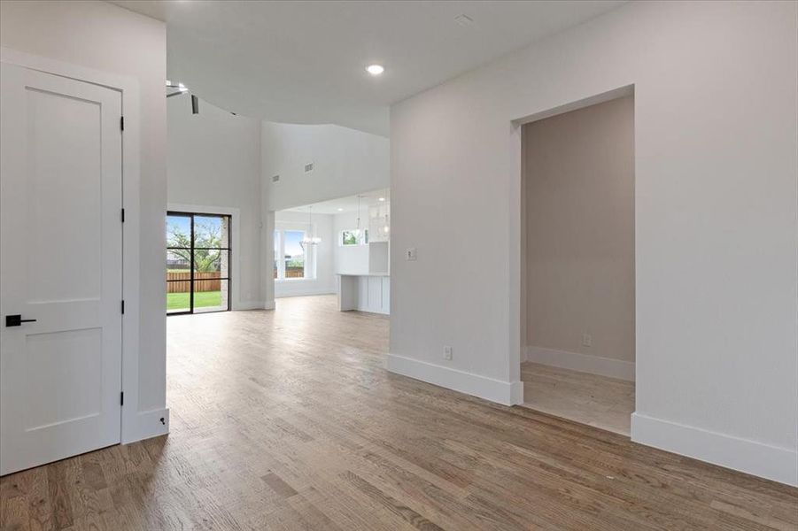 Empty room with high vaulted ceiling and hardwood / wood-style floors