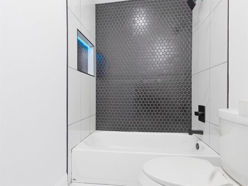 Bathroom with toilet and tiled shower / bath