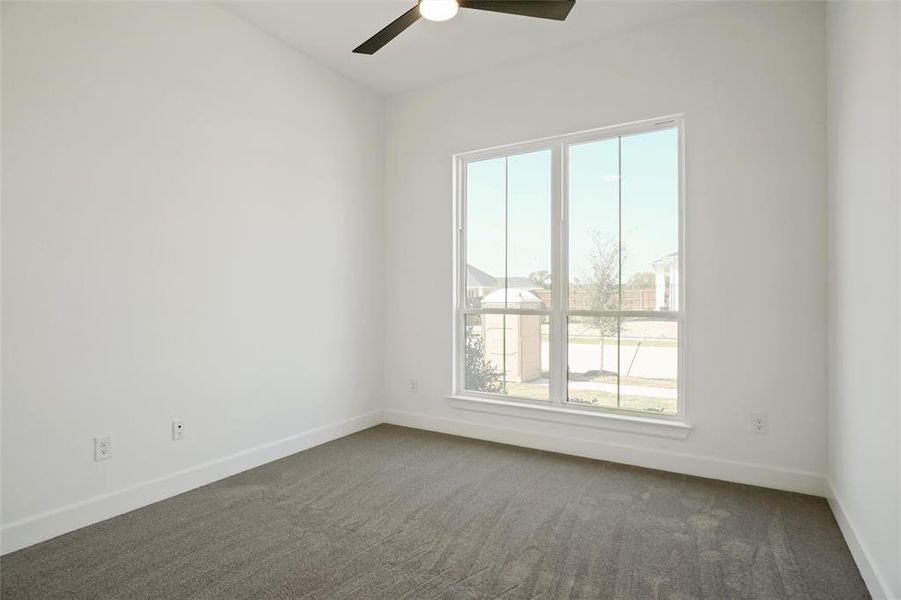 Unfurnished room featuring dark colored carpet and ceiling fan