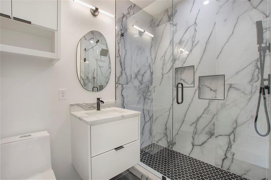 Bathroom with tile flooring, walk in shower, oversized vanity, and toilet