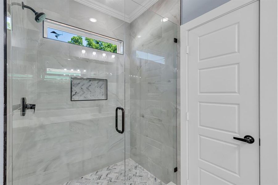 Bathroom featuring crown molding and a shower with shower door