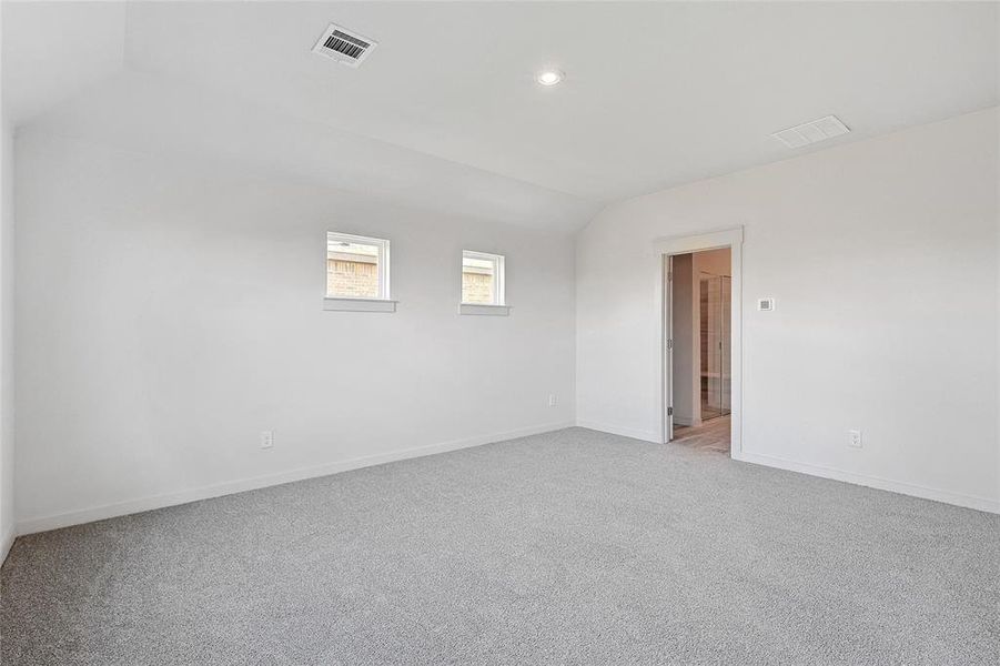 Empty room with light carpet and vaulted ceiling