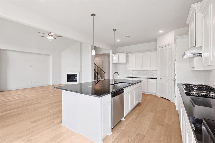 Kitchen featuring light hardwood / wood-style floors, appliances with stainless steel finishes, an island with sink, white cabinets, and sink