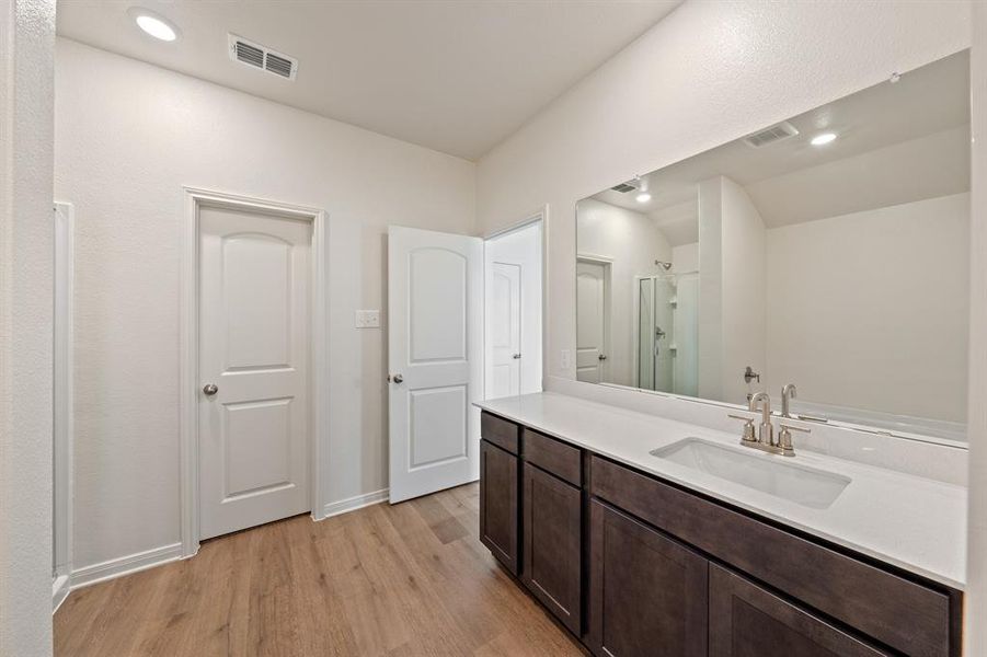 Bathroom featuring wood-style flooring, vanity, and a shower with shower door