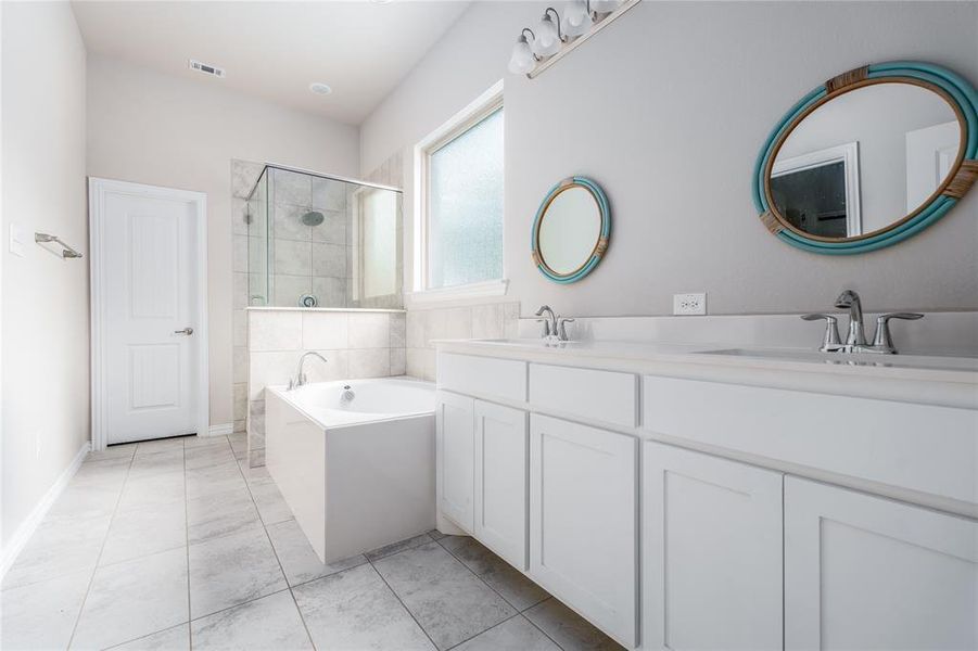 Bathroom featuring plus walk in shower, tile patterned floors, and double sink vanity