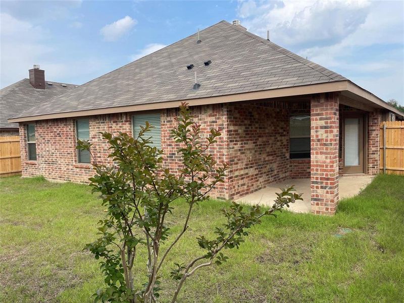 View of side of property featuring a lawn and a patio