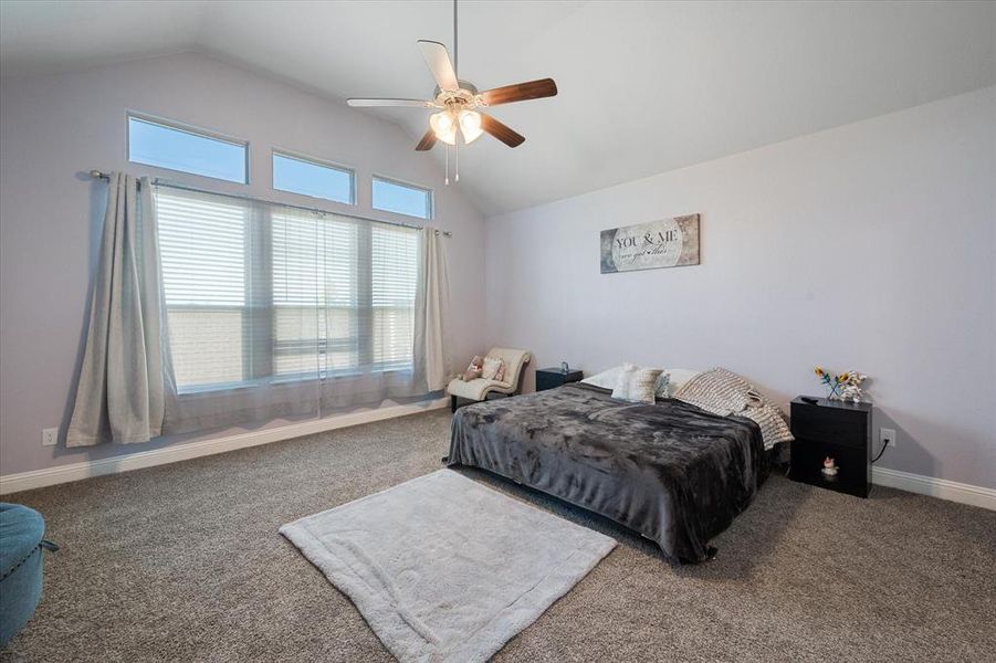 Primary Bedroom carpeted featuring vaulted ceiling and ceiling fan