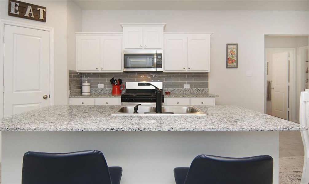 Kitchen with sink, white cabinetry, a kitchen breakfast bar, and an island with sink