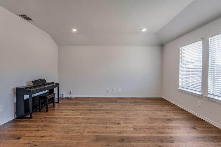 Empty room featuring lofted ceiling and dark hardwood / wood-style flooring