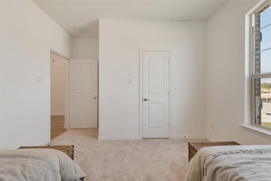 Bedroom with light carpet and multiple windows