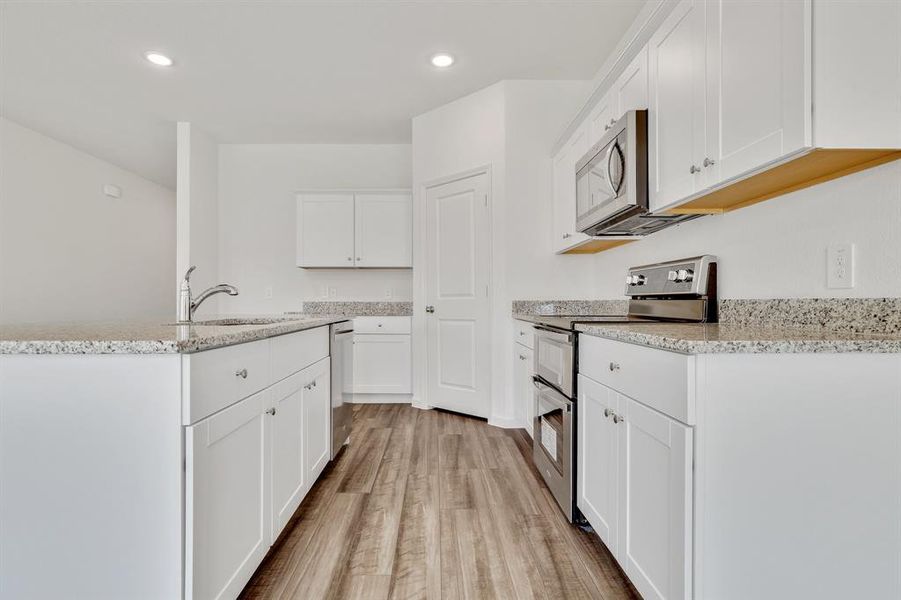 Kitchen featuring stainless steel appliances, white cabinetry, light wood-type flooring, and sink