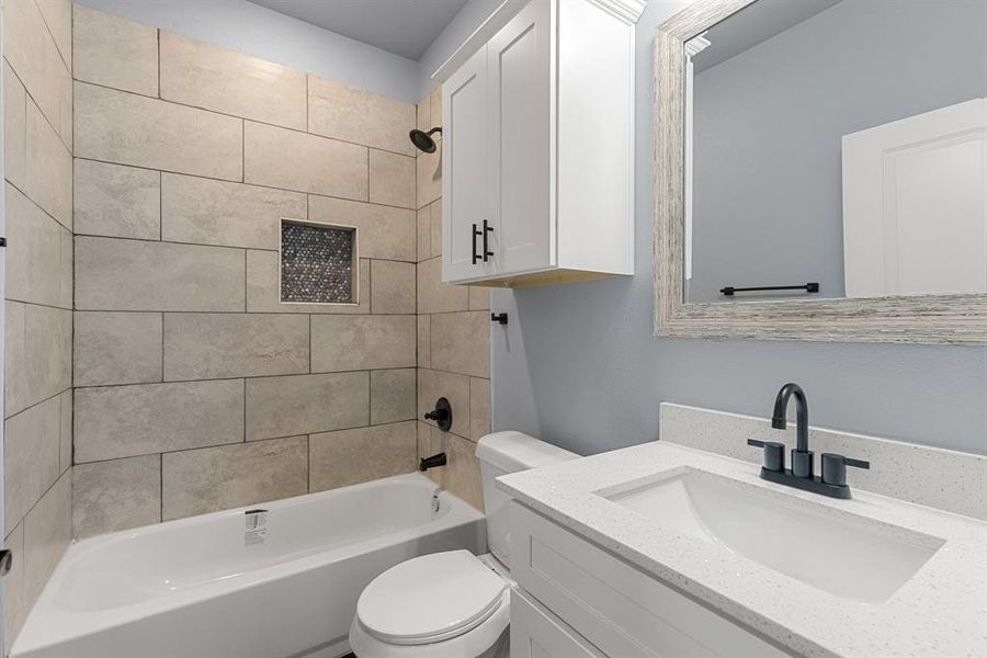 Full bathroom with vanity, tiled shower / bath combo, and toilet